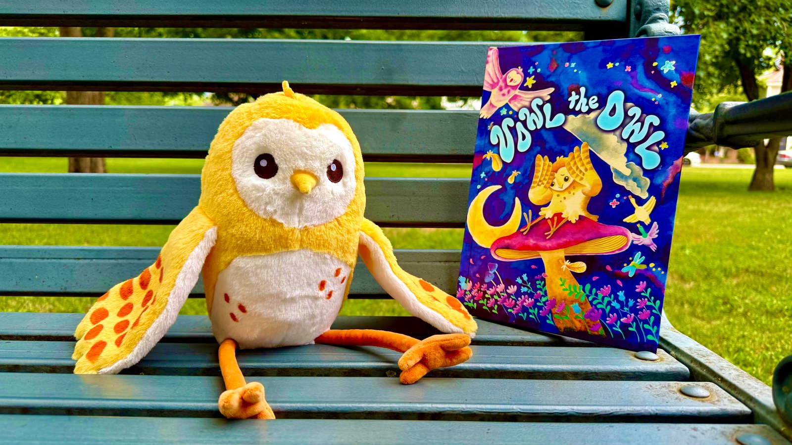 Vowl the Owl plushie sitting beside the book on a park bench